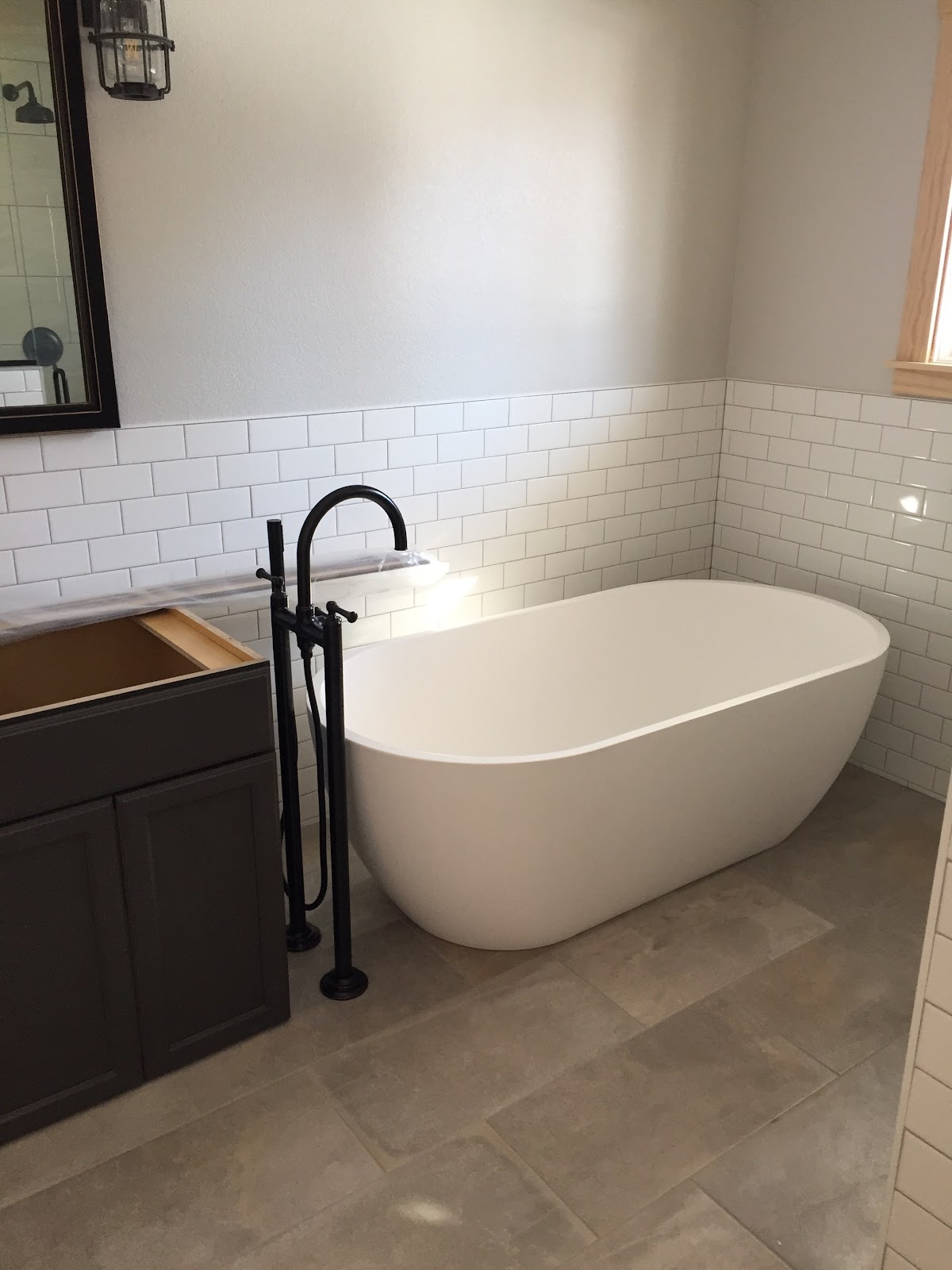 Freestanding white bathtub with a black floor-mounted tub filler