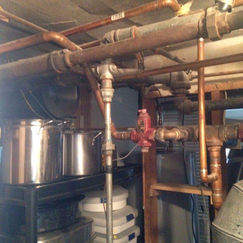 Copper and iron supply piping in a basement mechanical room